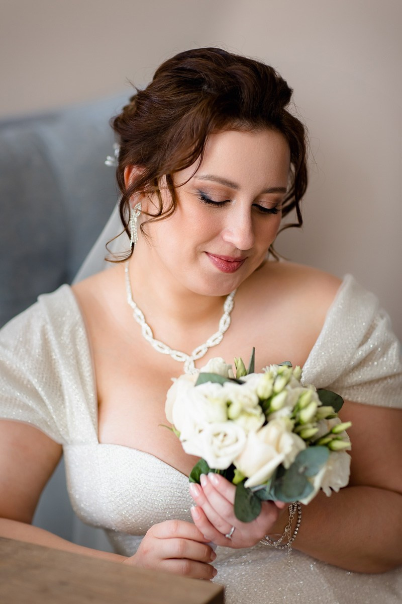 Невеста сидит в кресле и смотрит на букет