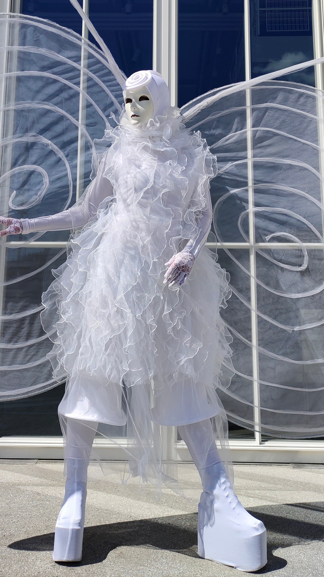 Пеший мим в образе белой бабочки на встрече гостей на свадьбе.