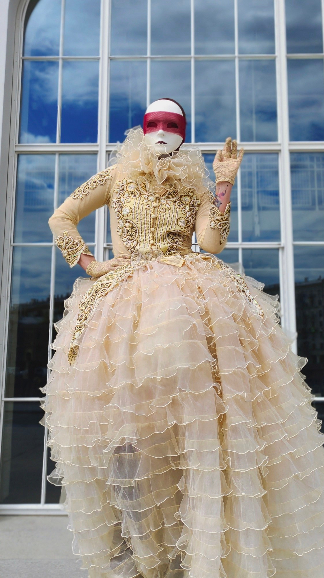 Мим позирует фотографу на фотосессии на фоне большого окна на весь рост.