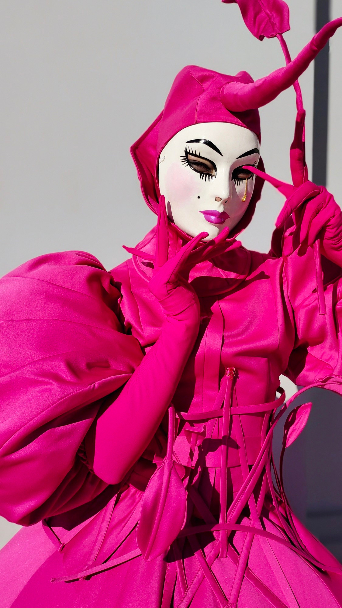 Мим в маске со слезой и с рогом на шляпе встречает гостей на свадьбе.