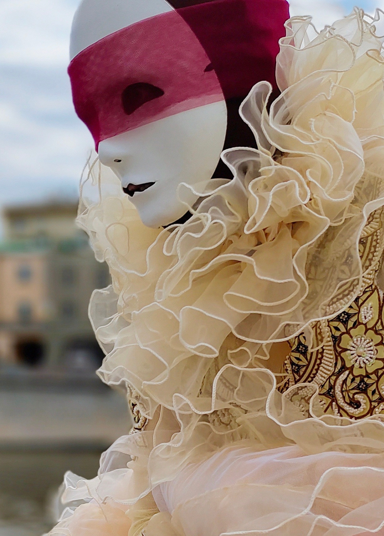 Мим в белой маске с красной повязкой и шикарным воротником.