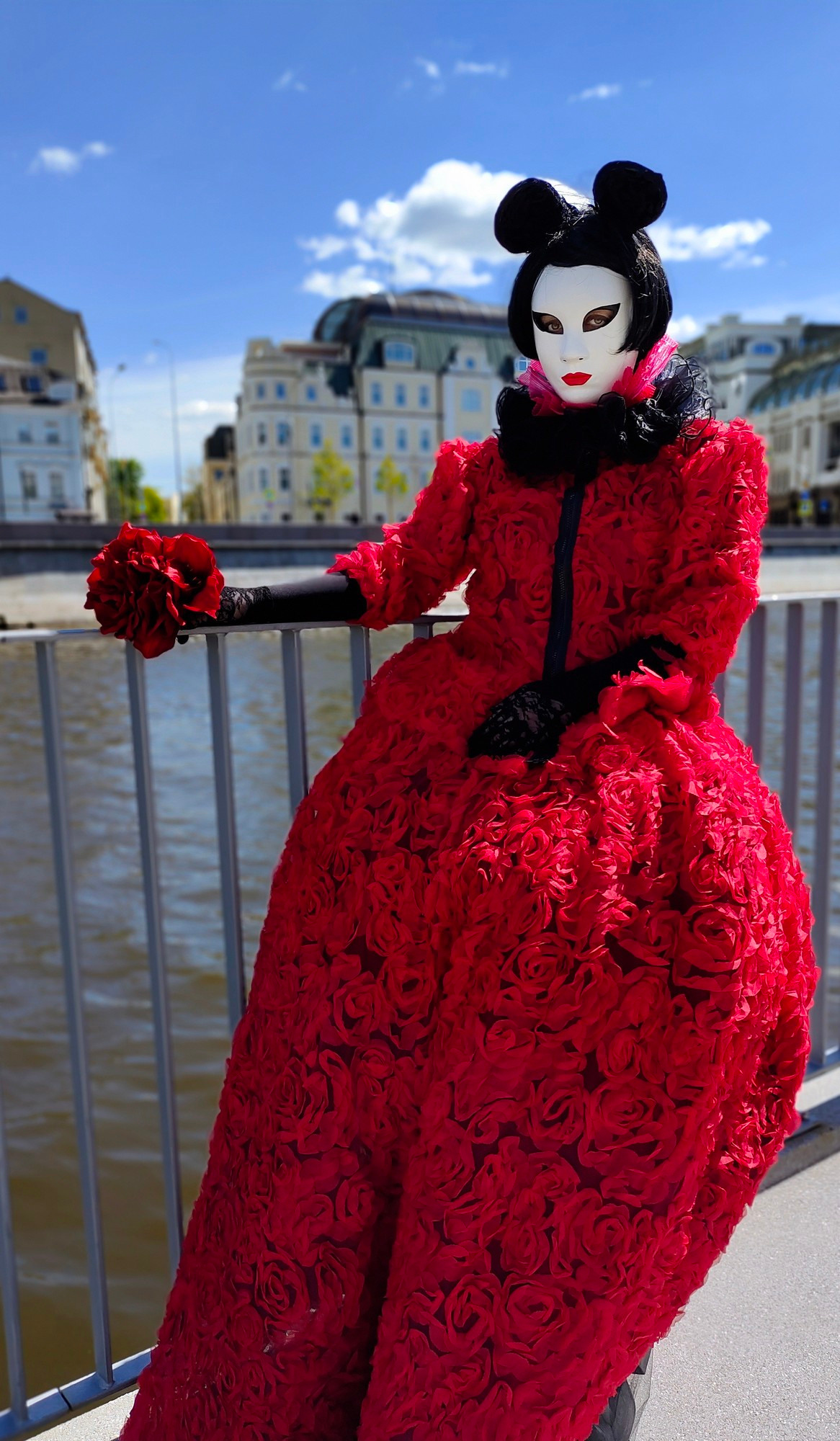 Артист в красном платье мим Мышка от лисавлесу с букетом невесты ожидает гостей на набережной.
