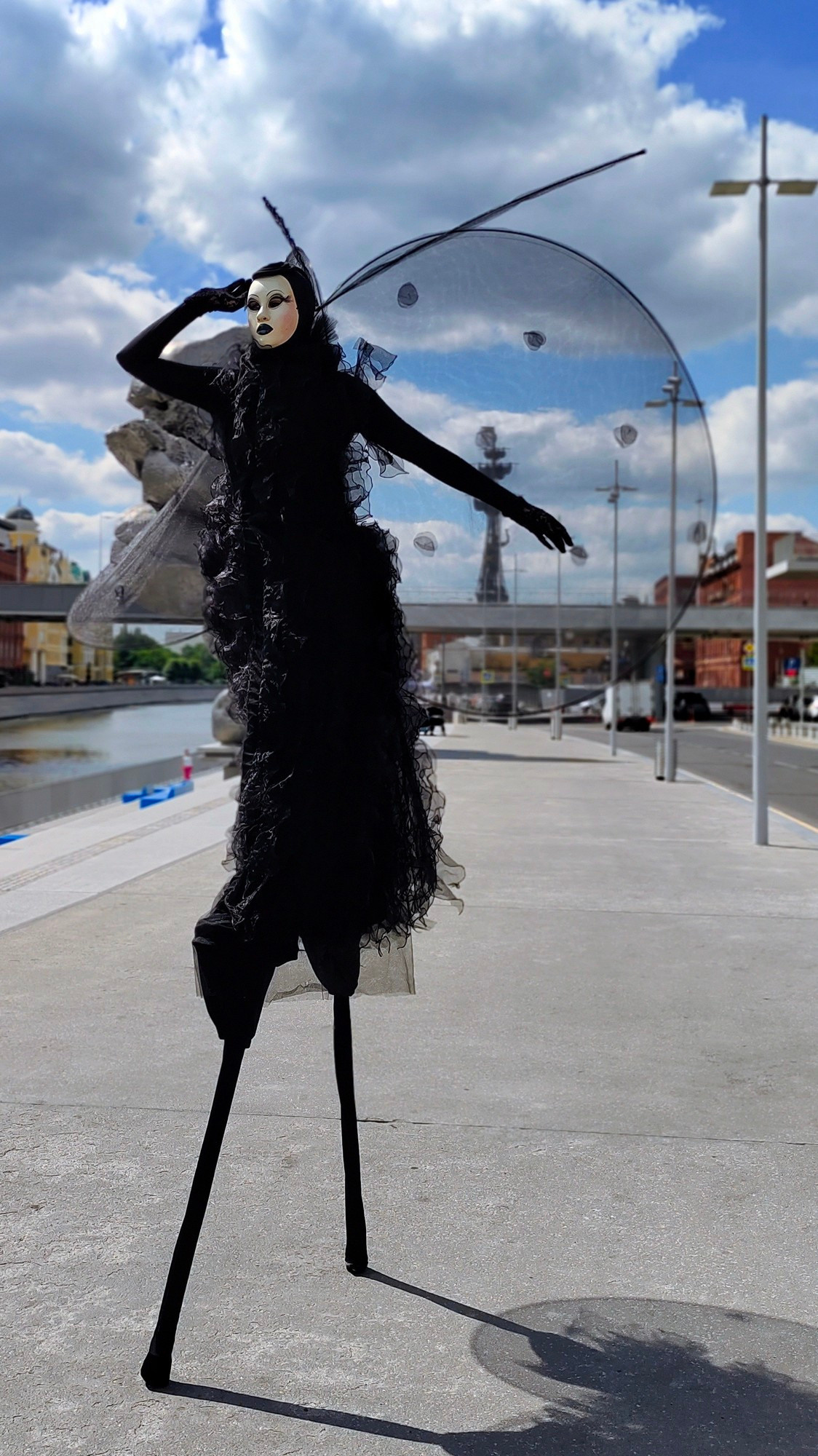 Артист на ходулях в образе прячется от яркого солнца. 