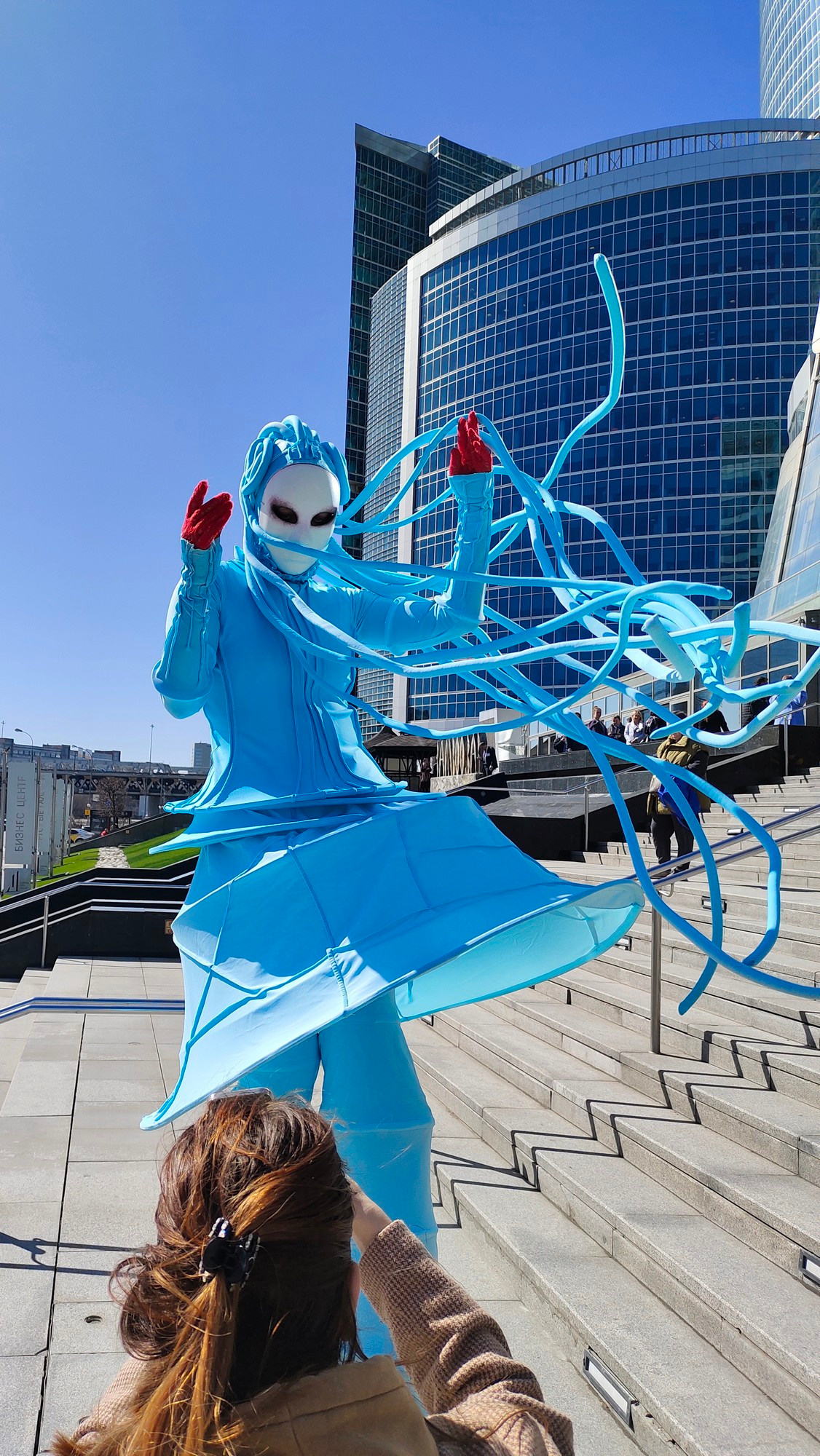 Ходулист разбрасывает волосы-дреды позируя для фотографа на мероприятии. 