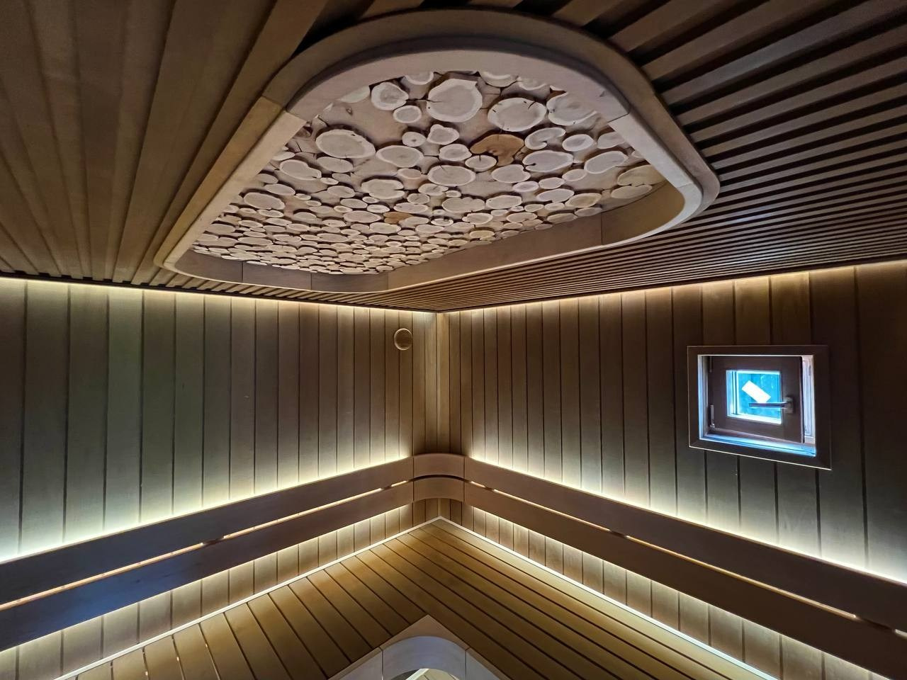 Парная в Колосе по индивидуальному проекту с реечным потолком, плавными линиями радиальных элементов и теплой закарнизной подсветкой. SaunaTopMasters