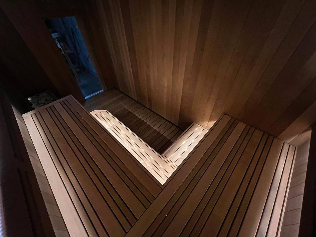 Сауна в Керро из разноширокой термоольхи. Ламповый свет термостойких лент и закарнизная подсветка плитки из талькохлорита 300×300мм. SaunaTopMasters