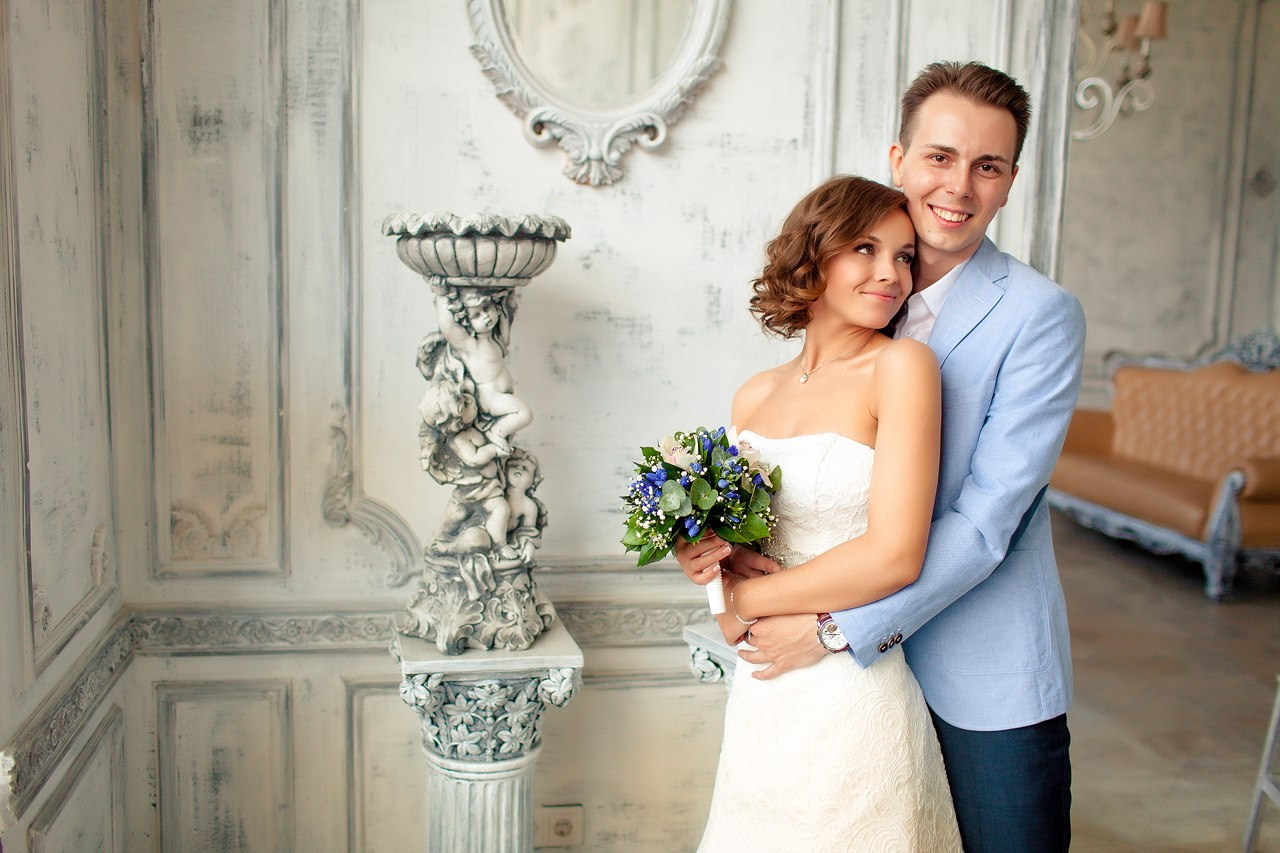 молодожены во дворце бракосочетания фотографируются рядом с красивой вазой 