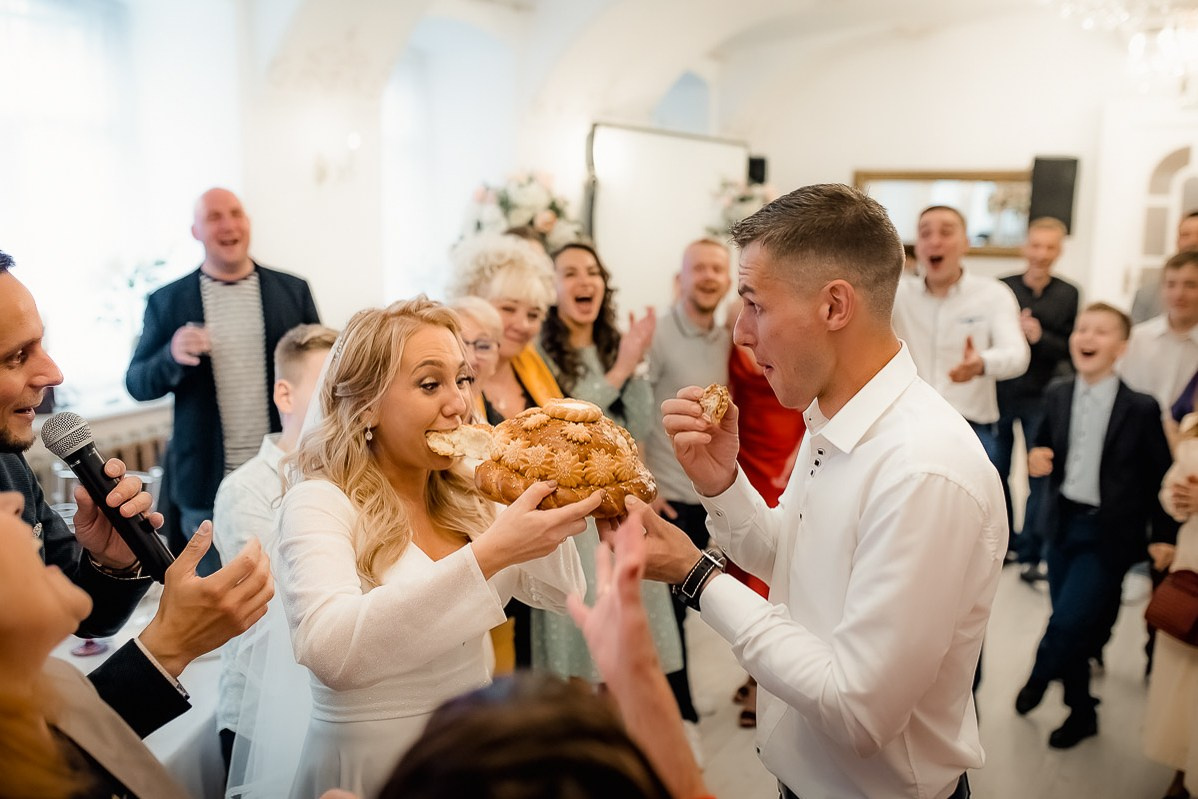 Жених и невеста откусывают хлеб в ресторане в Санкт-Петербурге.  Горизонтальный  поясной кадр.