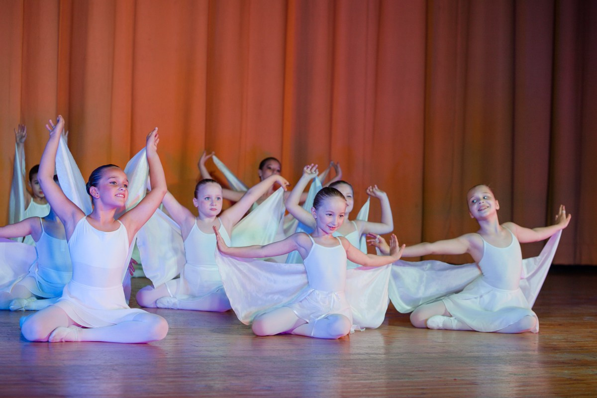 Девочки в Белых костюмах с крыльями танцуют на сцене Одинцовского дома культуры