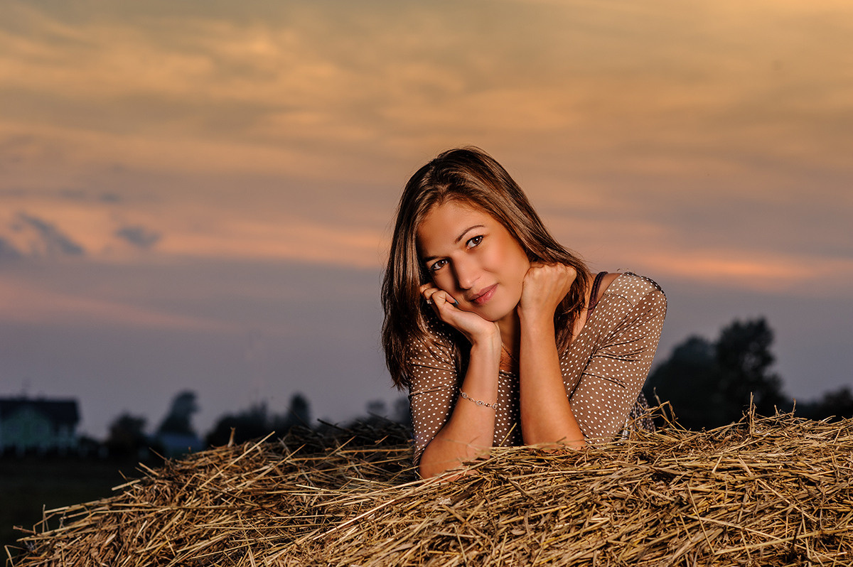 девушка лежит на сене на фоне красивого заката
