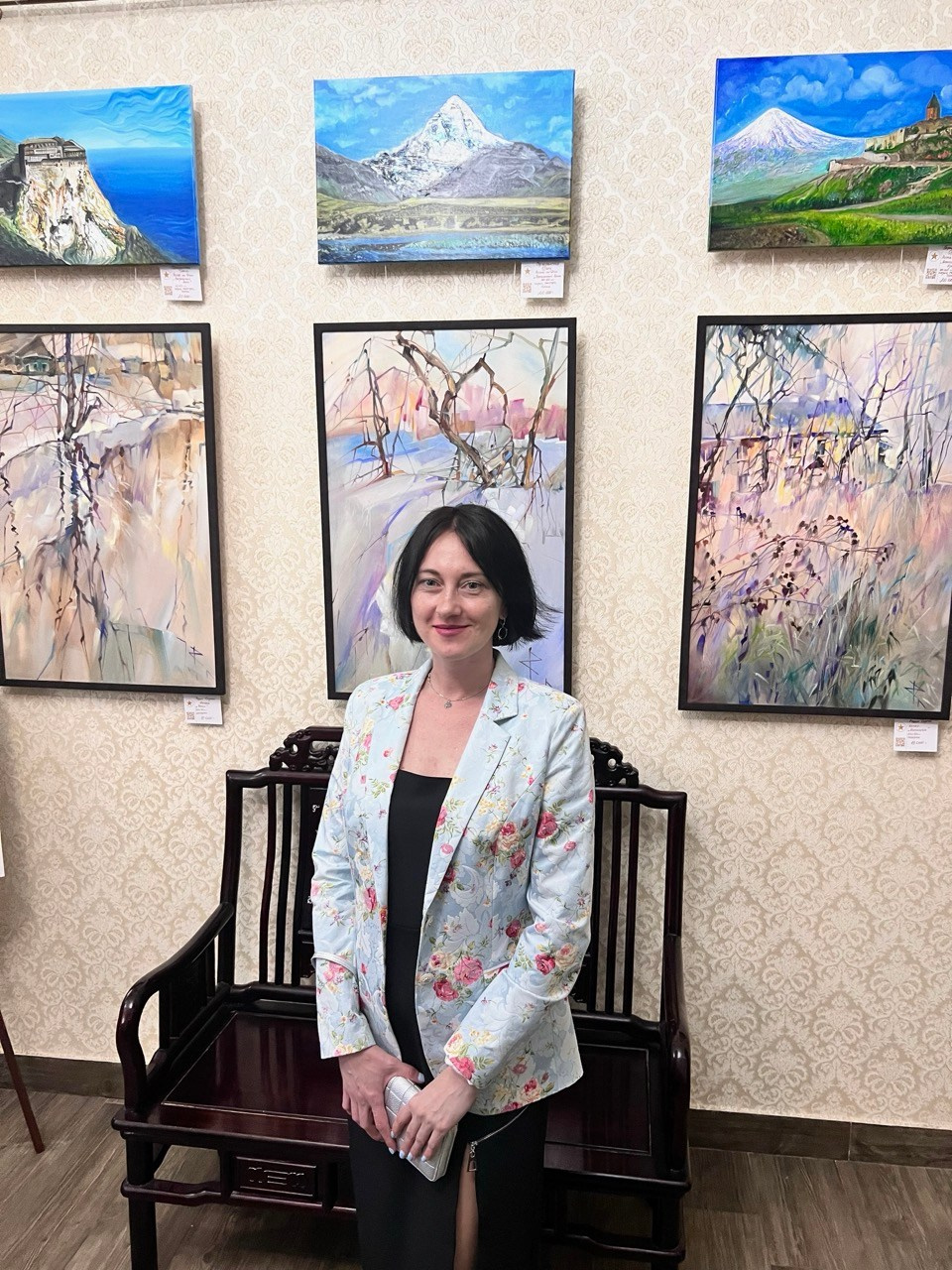 коллективная выставка пейзажей, художник стоит со своими картинами