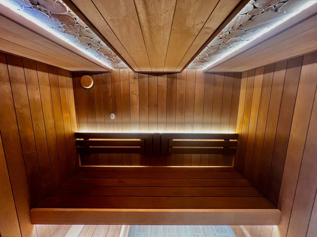 Сауна в Рощино на базе электрокаменки с парогенератором Harvia Virta выполнена из термоольхи с интеграцией световых линий из можжевельника. SaunaTopMasters