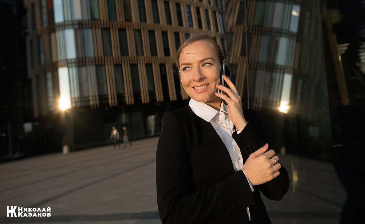 Активная молодая руководительница общается с коллегой по смартфону 