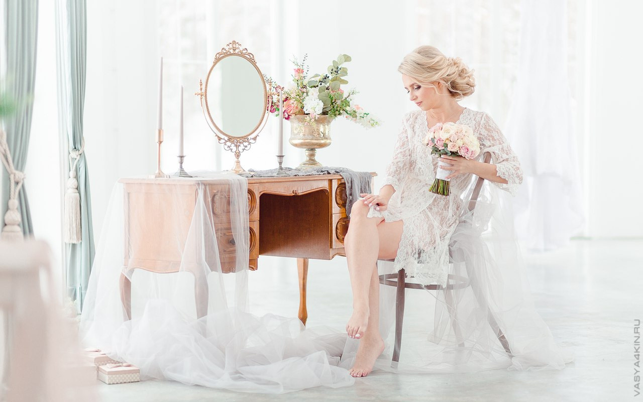 Пара, играющая в футбол вместе на траве в белоснежных свадебных нарядах, мимо них пролетают многоцветные мыльные пузыри