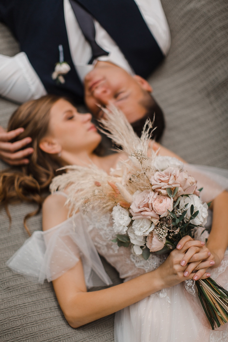 Молодожены прогуливаются по дорожке, усыпанной цветочными лепестками, на фоне дворца в Ярославле