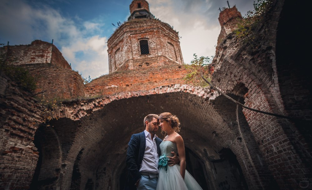 Невеста и жених стоят на обрыве скалы, симолизирующим начало их совместного приключения, на этой динамичной свадебной фотографии