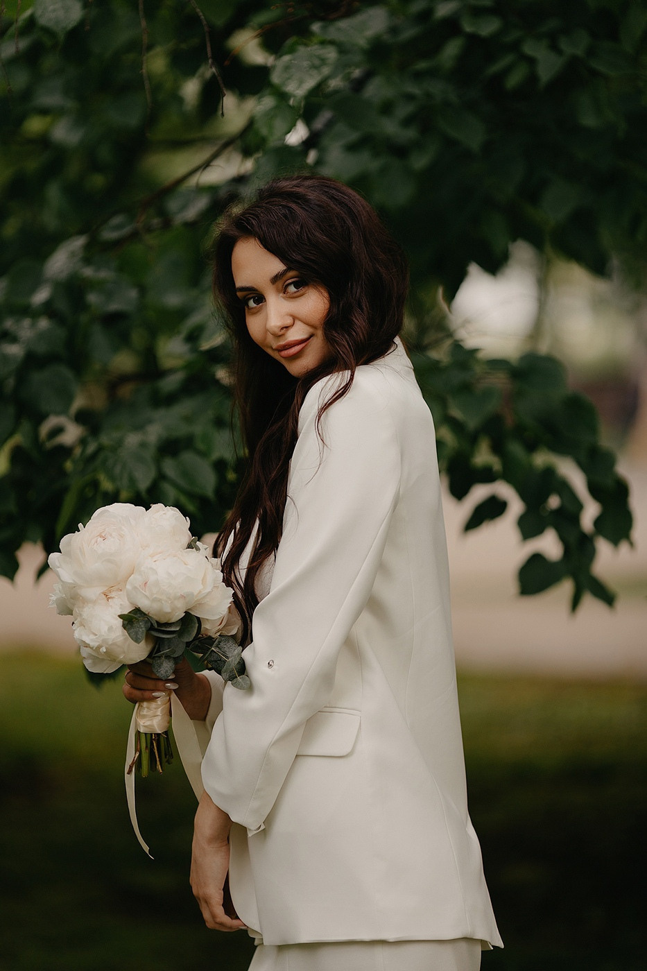 Невеста и жених, счастливые и влюбленные, держат друг друга за руки, улыбаясь и смотря друг на друга взглядом, полным любви