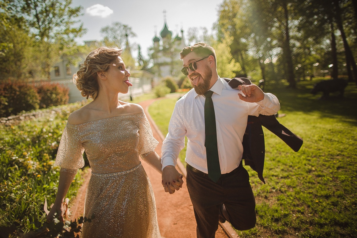 Молодожены идут по дорожке с белыми розами, на фоне дворца, украшенного осенними цветами, на своей гламурной свадьбе в Ярославле