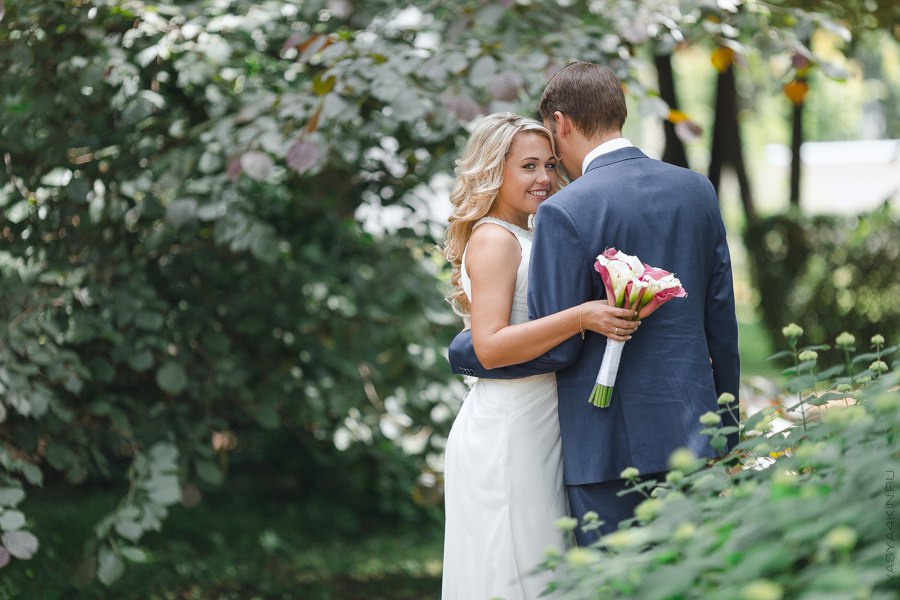 Жених легко поддерживает невесту на этой свадебной фотографии, словно готов ей помочь в любых ситуациях