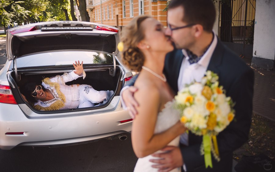 Молодые, целующиеся под падающим дождем, освещенные разноцветным огнем