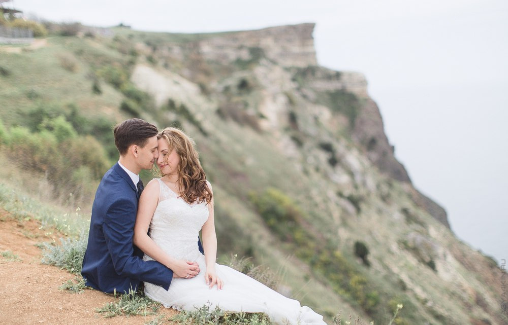 Невеста и жених стоят у вершины горы, словно они готовы преодолеть все трудности и преграды, на этой замечательной свадебной фотографии