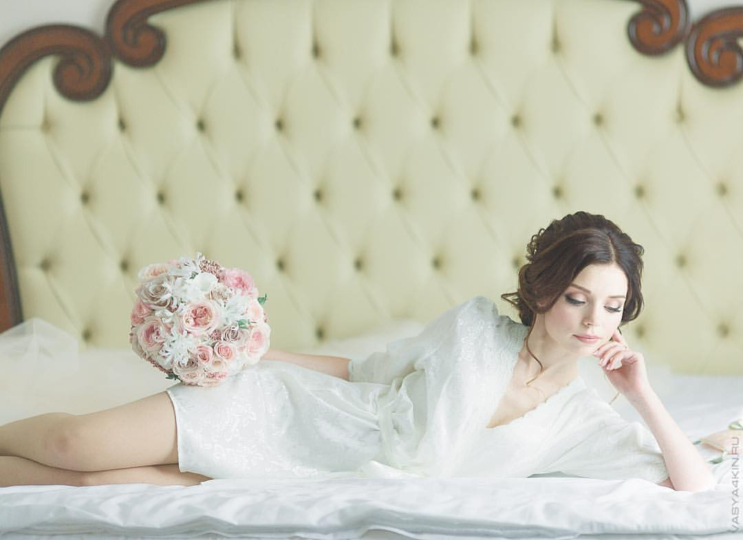 Невеста и жених прыгают на катушках сена, окруженные композициями цветов и холмами, создавая атмосферу игривости и беззаботности