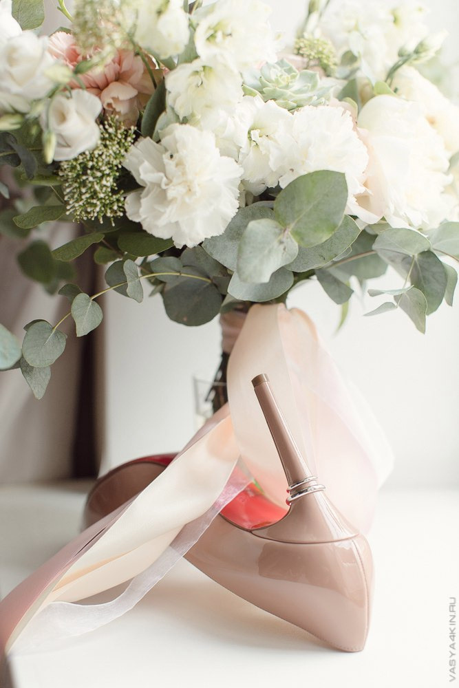 Нежный поцелуй молодых на фоне фонтана, который создает водные брызги вокруг них