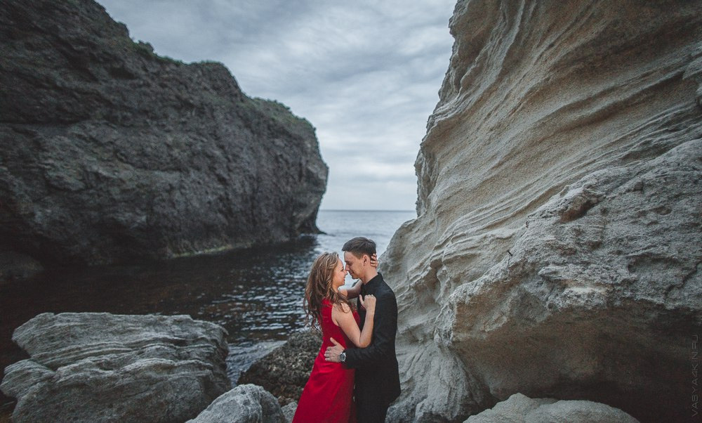 Молодая пара, стоящая на вершине горы, смотрящая на пейзаж с восхищением