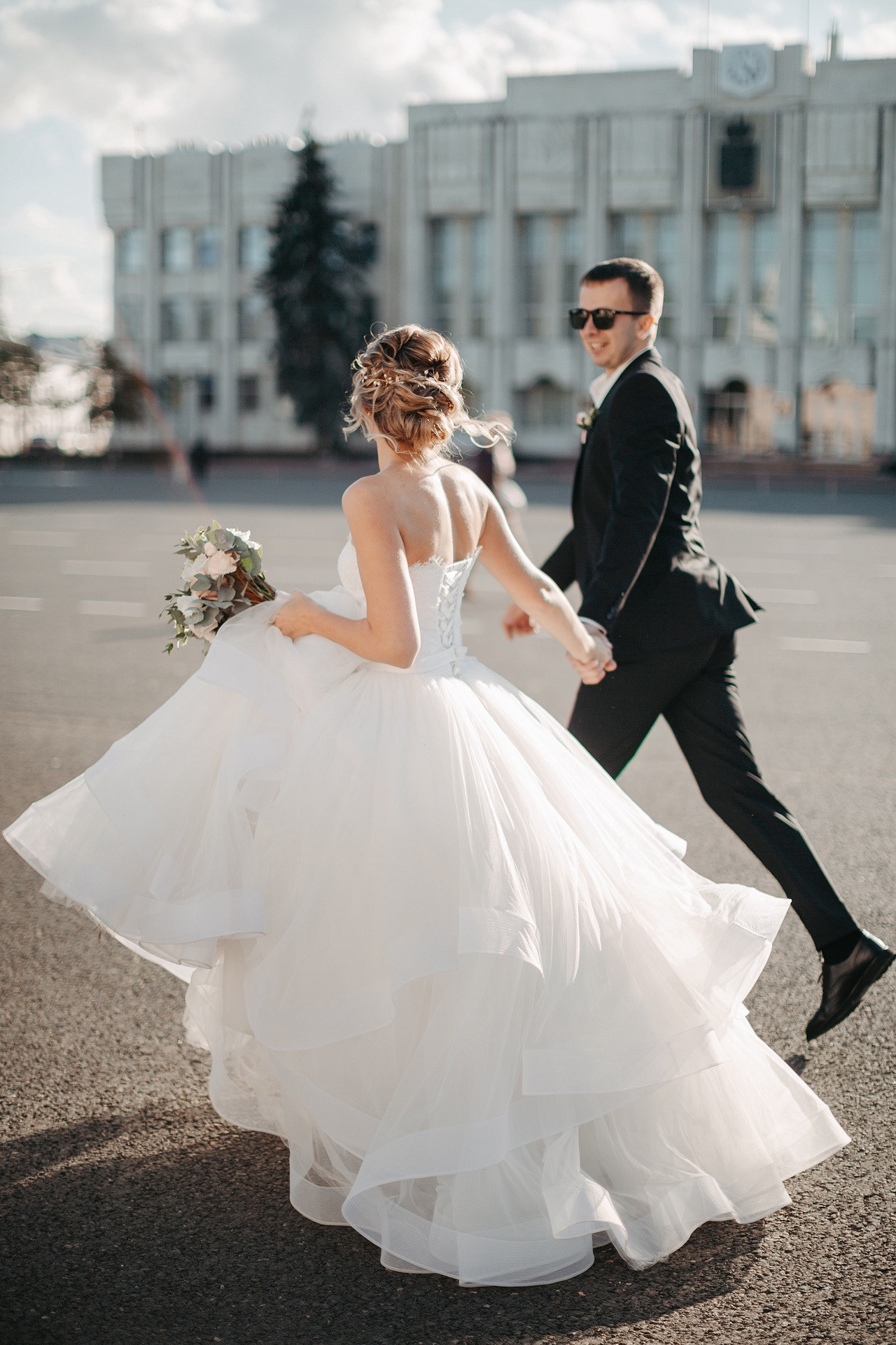 Пара сидит рядом на пляже, нежно обнявшись, словно время остановилось на этой идиллической свадебной фотографии