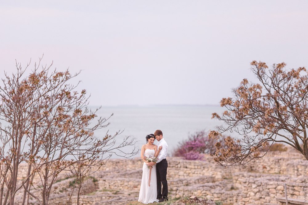 Невеста и жених смотрят на закат с вершины горы, создавая ощущение легкости и свободы, словно они покоряют мир вместе