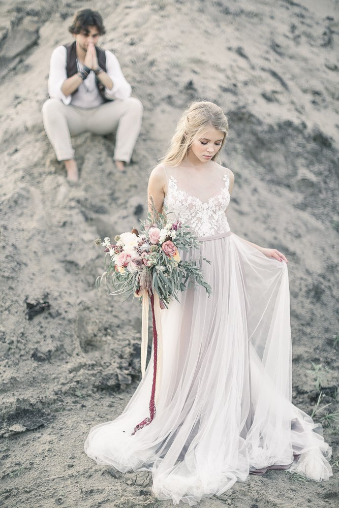 Новобрачные лежат на пледе в теплой осенней листве, смотря друг на друга и наслаждаясь моментом