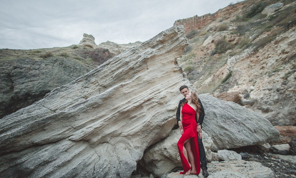 Молодая невеста в изящном прозрачном платье, смотрящая на закат