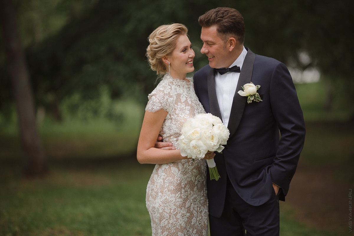 Молодожены держатся за руки, идя по дороге, узорчатая бетонная плитка которой подчеркивает их счастье и единство