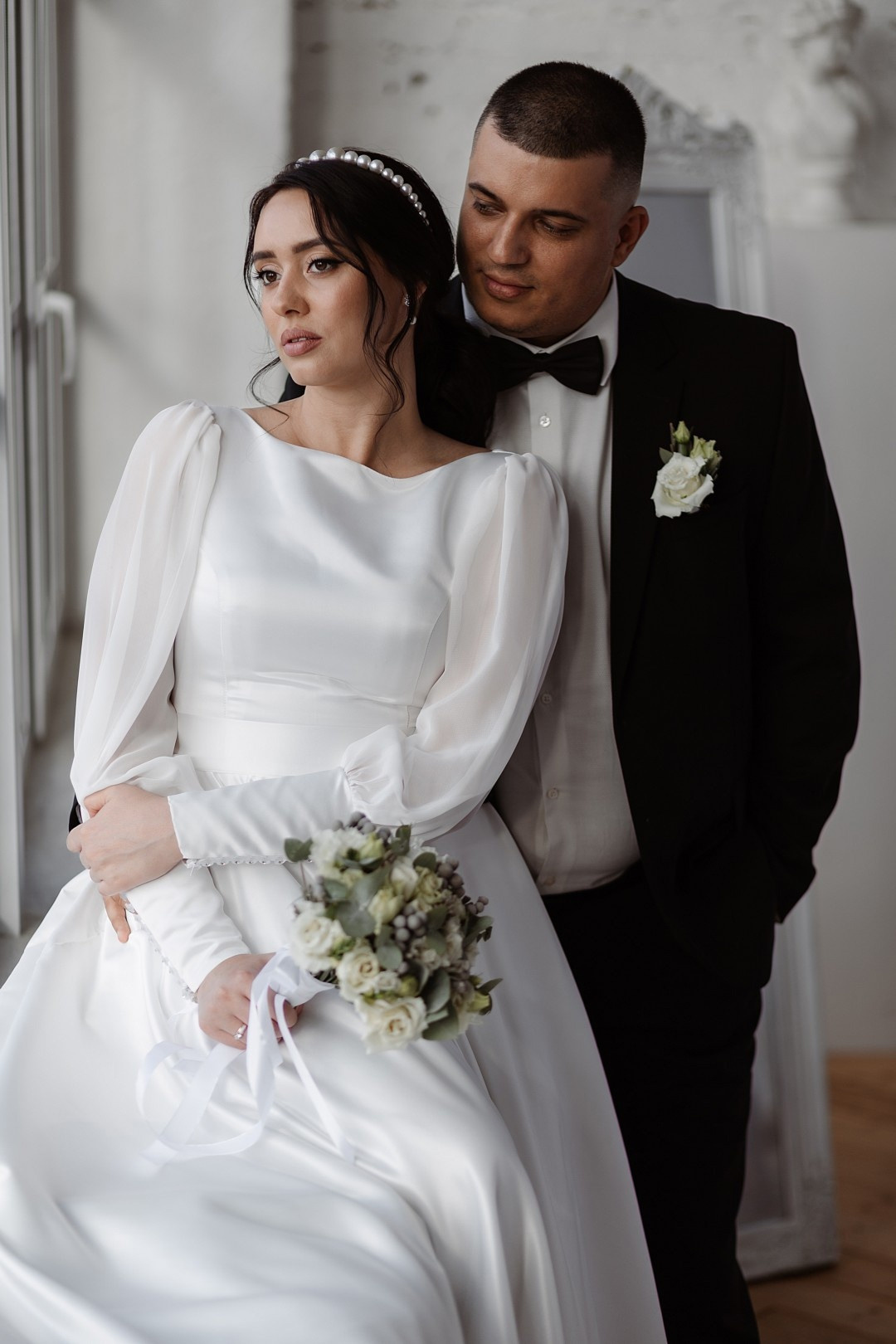 Невеста, сидящая на коленях молодого, смотрящего ей в глаза с яркой улыбкой