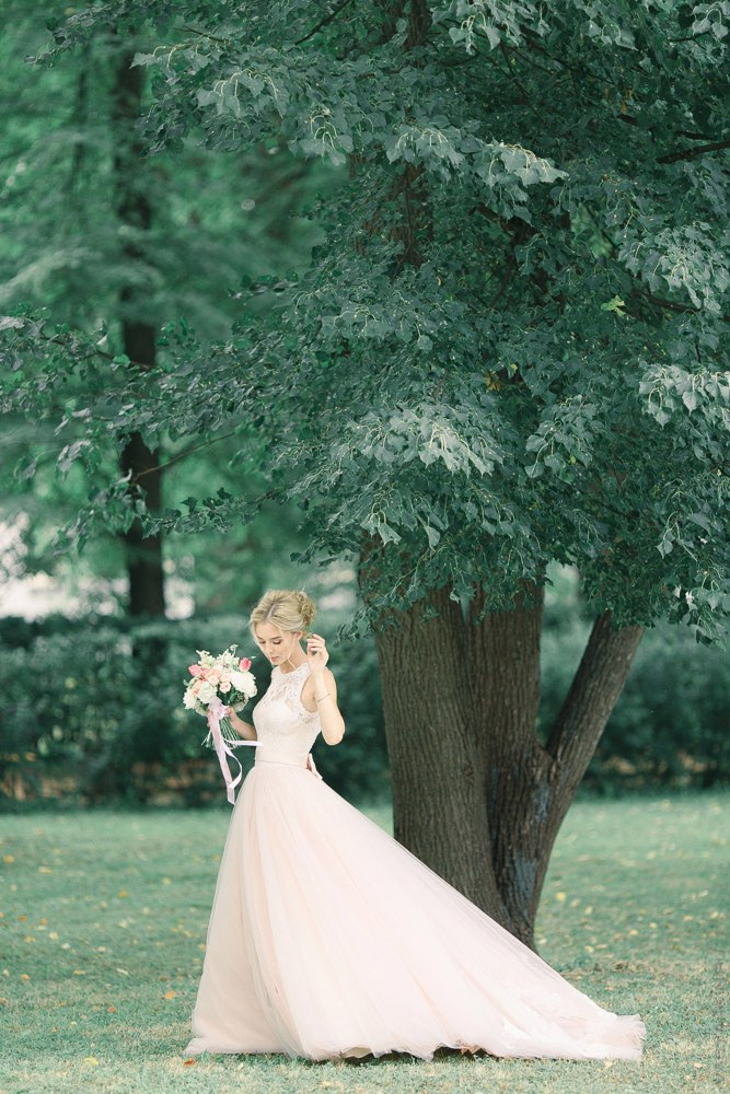 Пара, касающаяся губами друг друга на вершине горы, со снежными вершинами, окутанными нереальными розовыми облаками