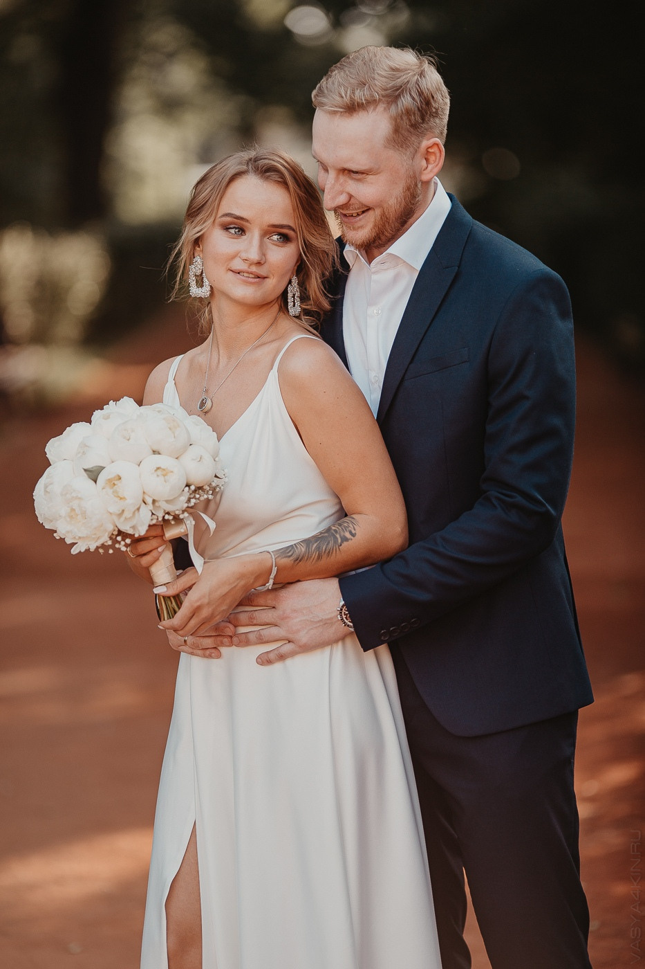 Молодые, целующиеся в декорированной арке с прозрачной тканью и светящимися ярко звездами