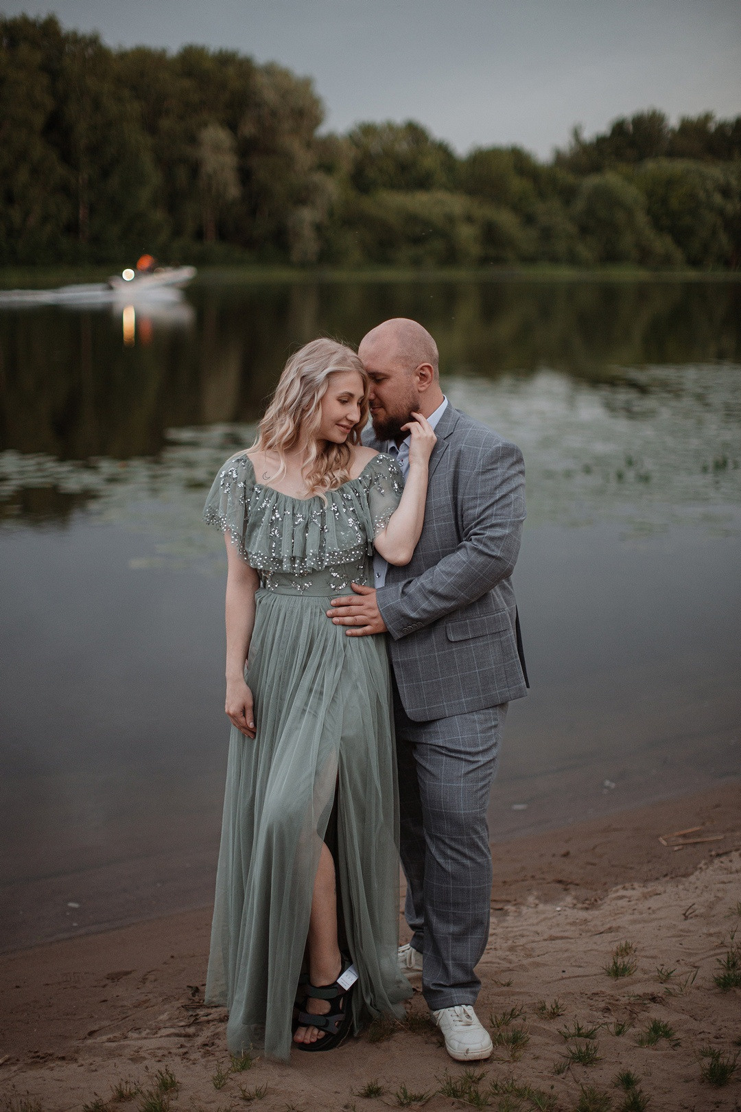 Свадебная фотография, на которой невеста и жених обнимаются на фоне красивейшего заката, создающего романтическую атмосферу