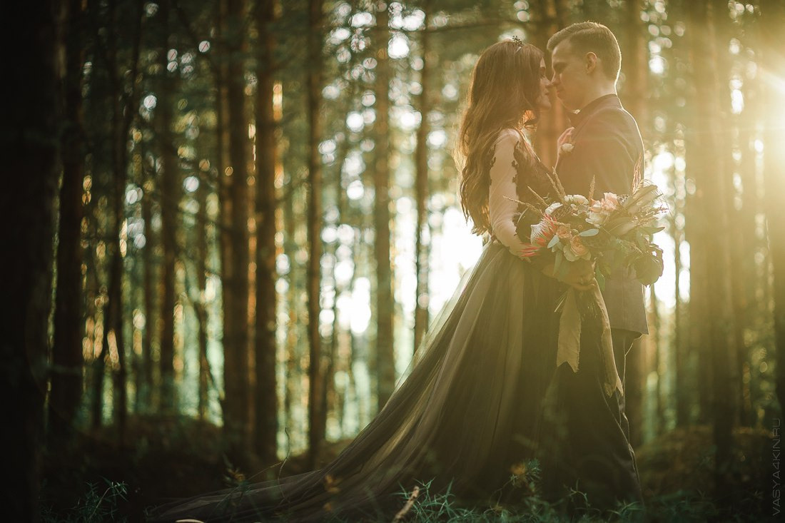 Новобрачные смотрят на закат на фоне деревни, создавая атмосферу сельской романтики и умиротворения