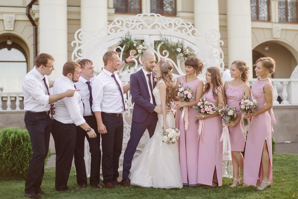 Снимок, запечатлевший влюбленных, идущих по аллее с цветочным узором, обрамленной великолепными зелеными деревьями