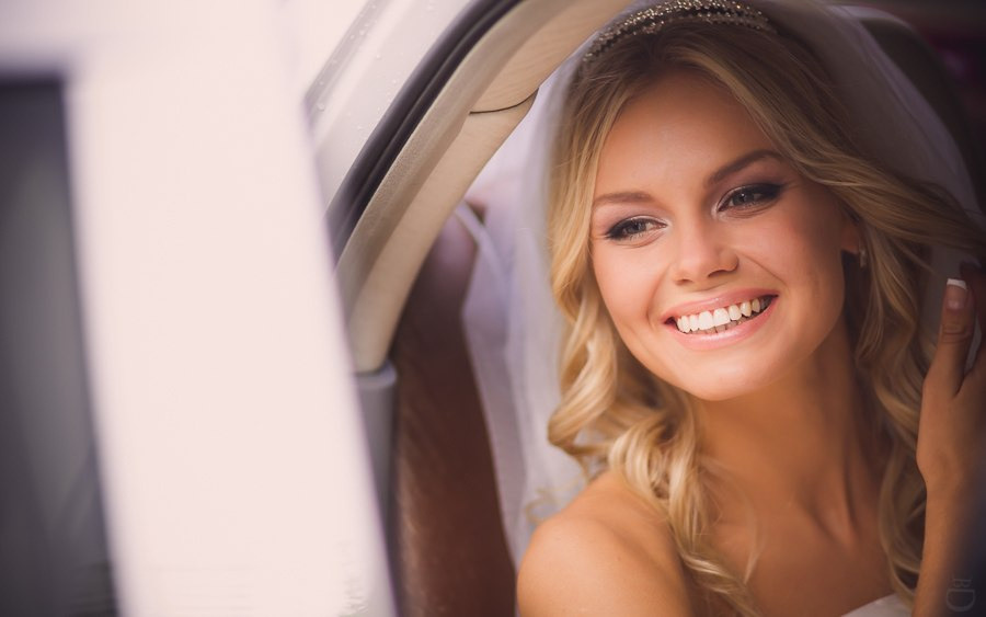 Фотография с дорогой свадьбы в Ярославле, где молодожены идут по дорожке с живыми цветами и светящимися факелами, вокруг них летают бабочки