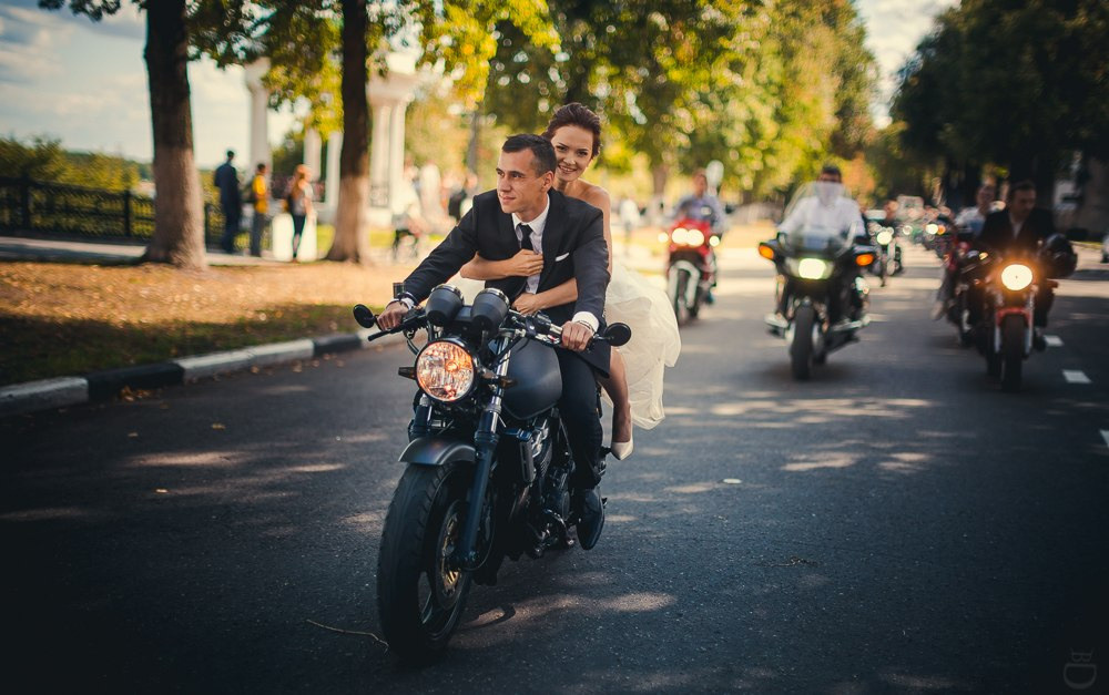 Свадебная фотография молодых, целующихся на фоне россыпи ярких осенних листьев