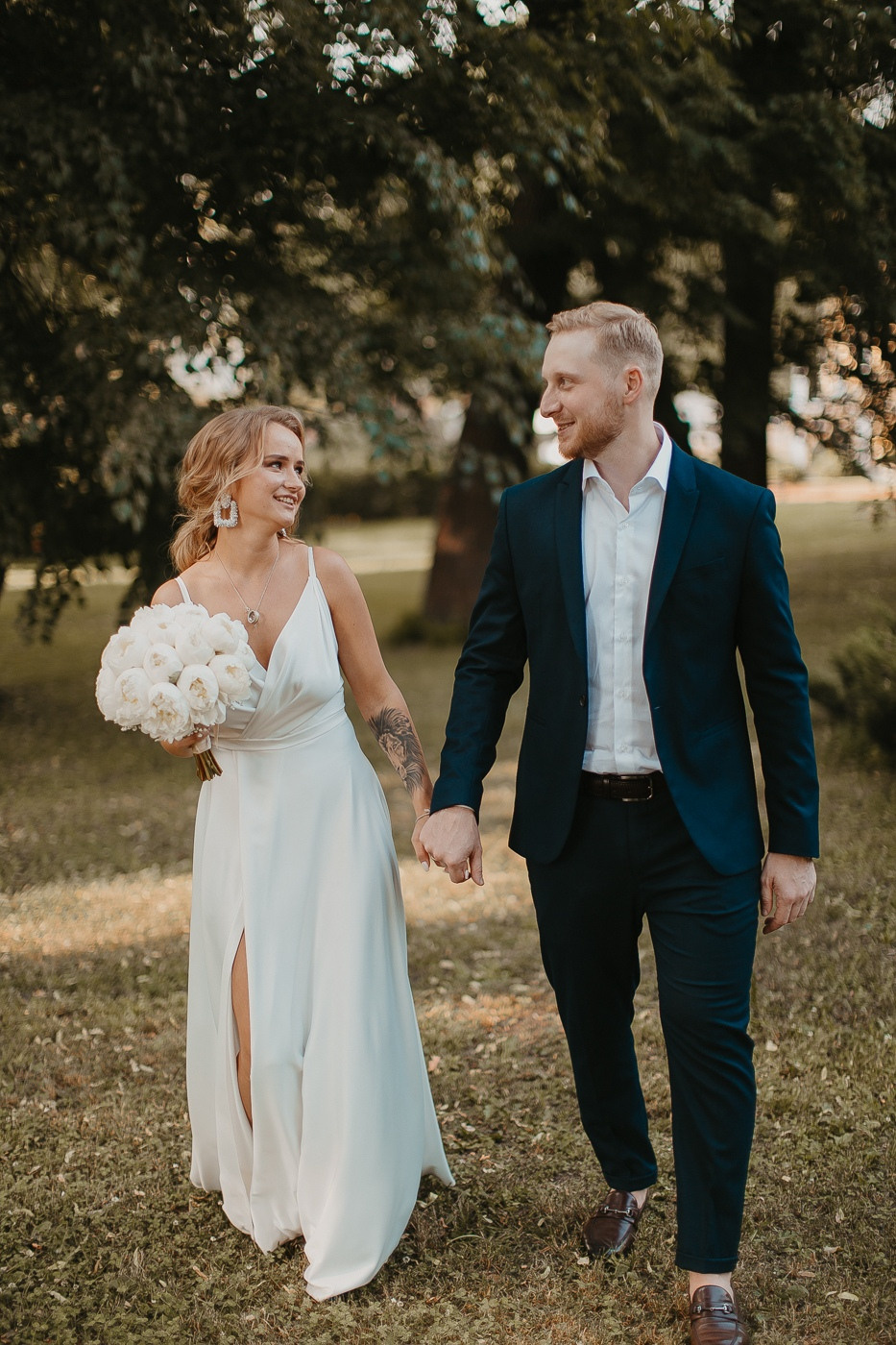 Фотография с дорогой свадьбы в Ярославле, где молодожены идут по дорожке с живыми цветами и светящимися факелами, вокруг них летают бабочки