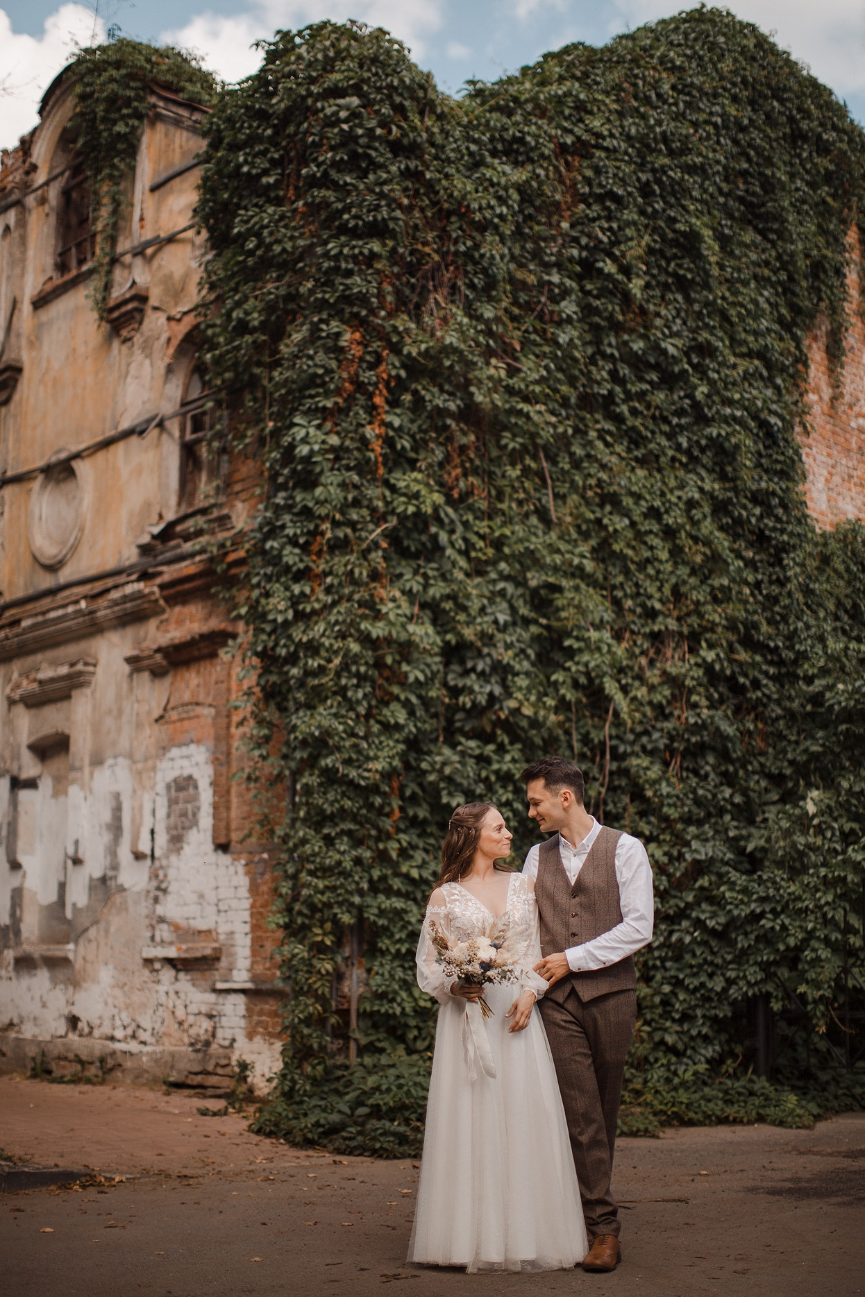 Молодожены на фоне роскошного дворца в Ярославле, идущие по дороге, усыпанной лепестками цветов, в их руках светящиеся факелы