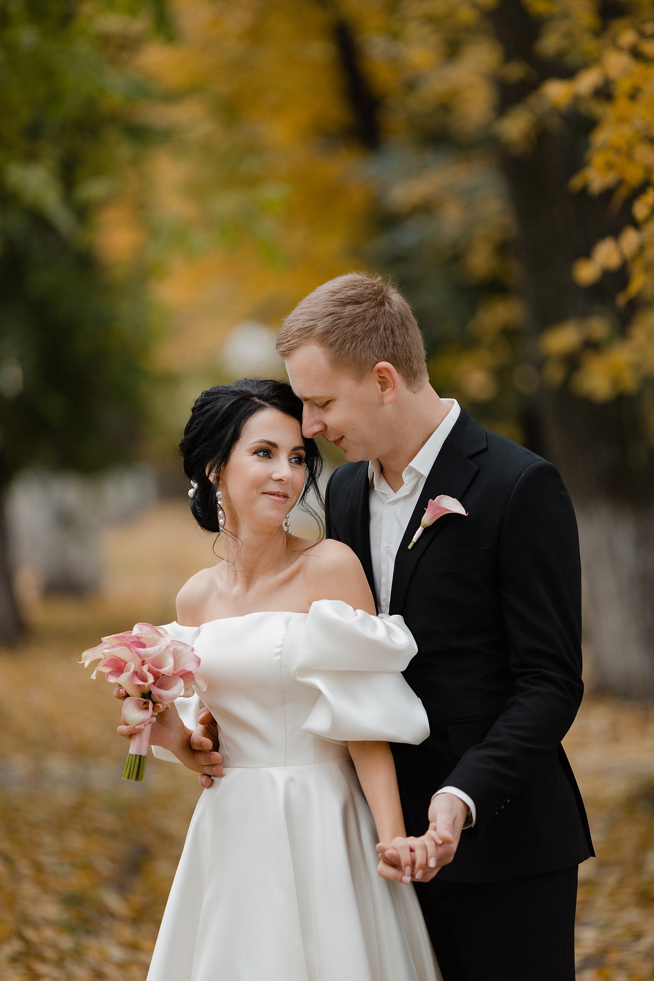 Молодожены, держащие друг друга за руки и идущие вместе по песчаному пляжу