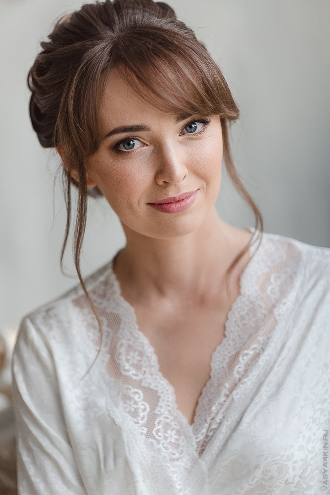 Свадебная фотография с невестой и женихом, стоящими на вершине горы, в окружении листвы и цветов, создающих ощущение волшебства и магии