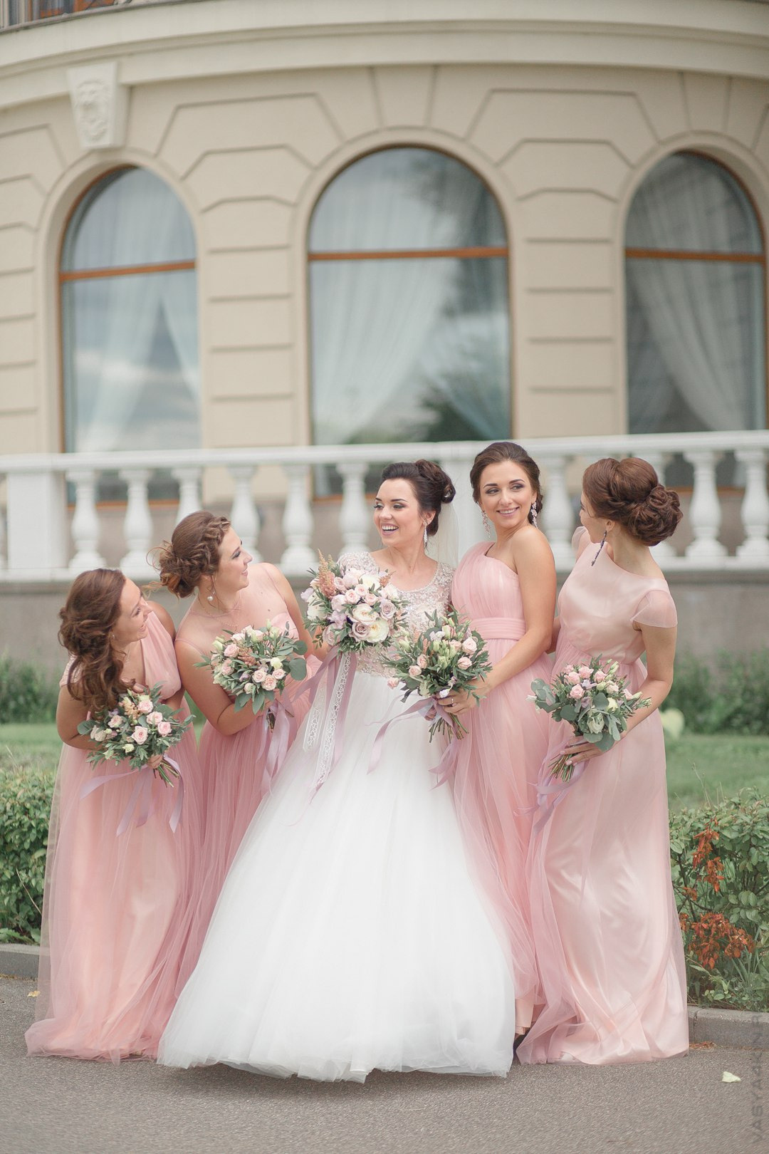 Невеста держит жениха за плечо, словно он ее лицемер и ее сила на этой красочной свадебной фотографии