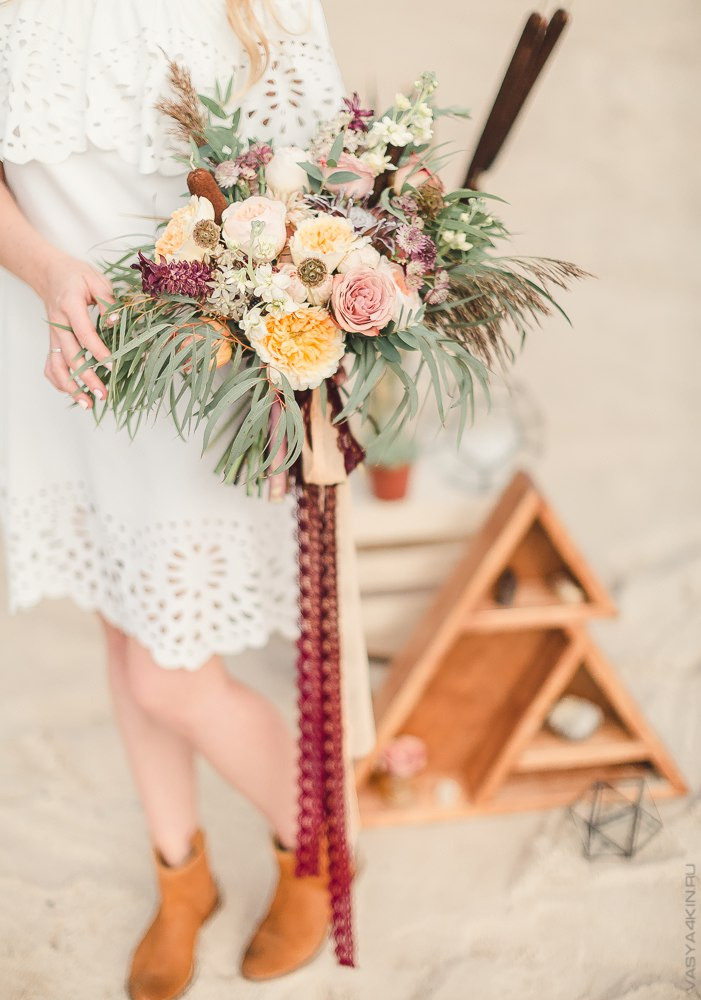 Снимок, на котором невеста и жених разговаривают на осенней поляне, окруженной деревьями, с падающим листьями и яркими цветами, создающими атмосферу умиротворения и спокойствия