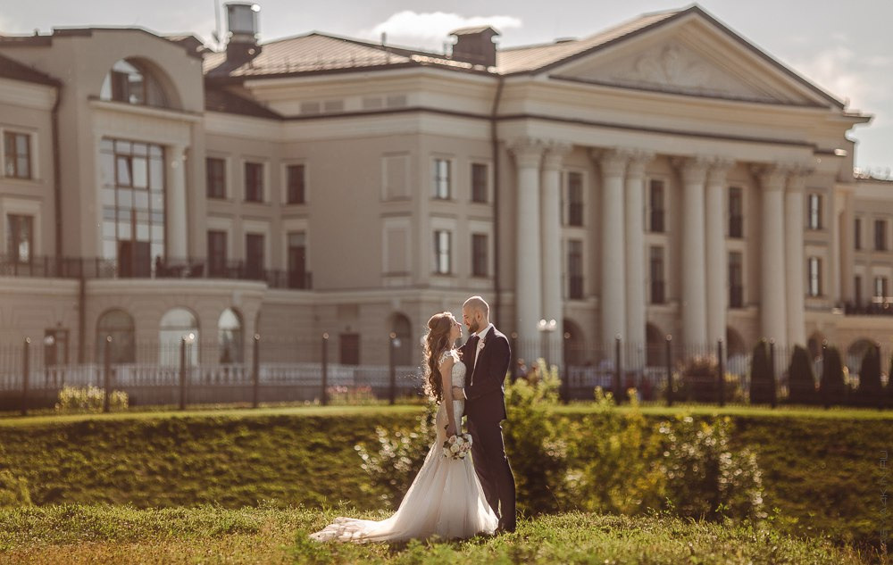 Свадебная фотография с невестой и женихом, прижимающими друг друга, на фоне города вечерним туманом, создающим романтическую атмосферу