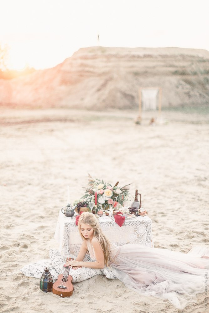 Молодые любовники, сидящие на песке, руки в руках, смотрящие на безрадостный океан с отражением искрящихся звезд