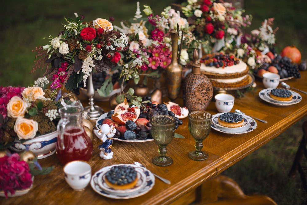 Подсвеченные свечами столы с цветами на фоне каминного зала, создают атмосферу уюта и стиля